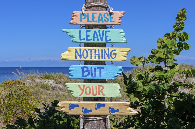 Bunter Wegweiser am Strand mit der Aufschrift „Please leave nothing but your…“