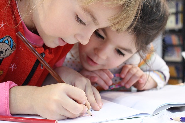 Zwei Kinder schreiben gemeinsam in ein Heft