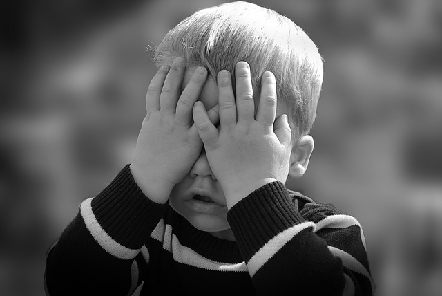 Kind hält sich die Hände vor die Augen, Schwarzweißaufnahme