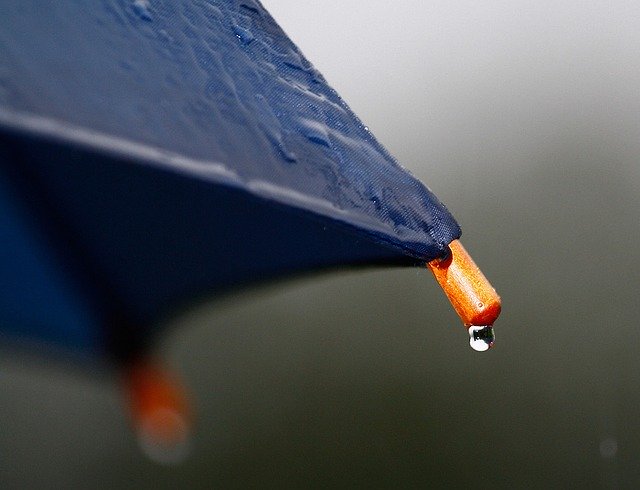 Regenschirm, an dessen Spitze ein Wassertropfen herabläuft
