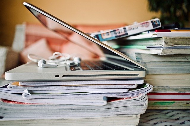 Aufgeklappter Laptop auf einem Stapel Zeitschriften