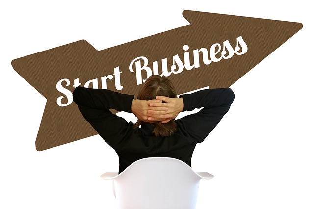 Wegweiser „Start Business“, dahinter eine Person mit verschränkten Armen