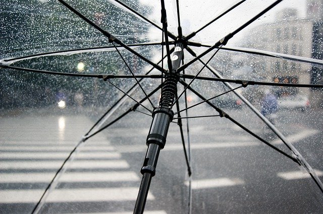 Aufgespannter Regenschirm im Regen über einer Straße