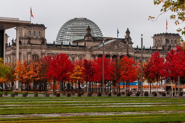 Reichstagsgebäude in Berlin, davor herbstlich rot gefärbte Bäume